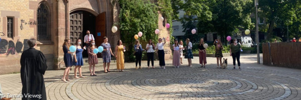 Junge Menschen mit Luftballons vor Kirche